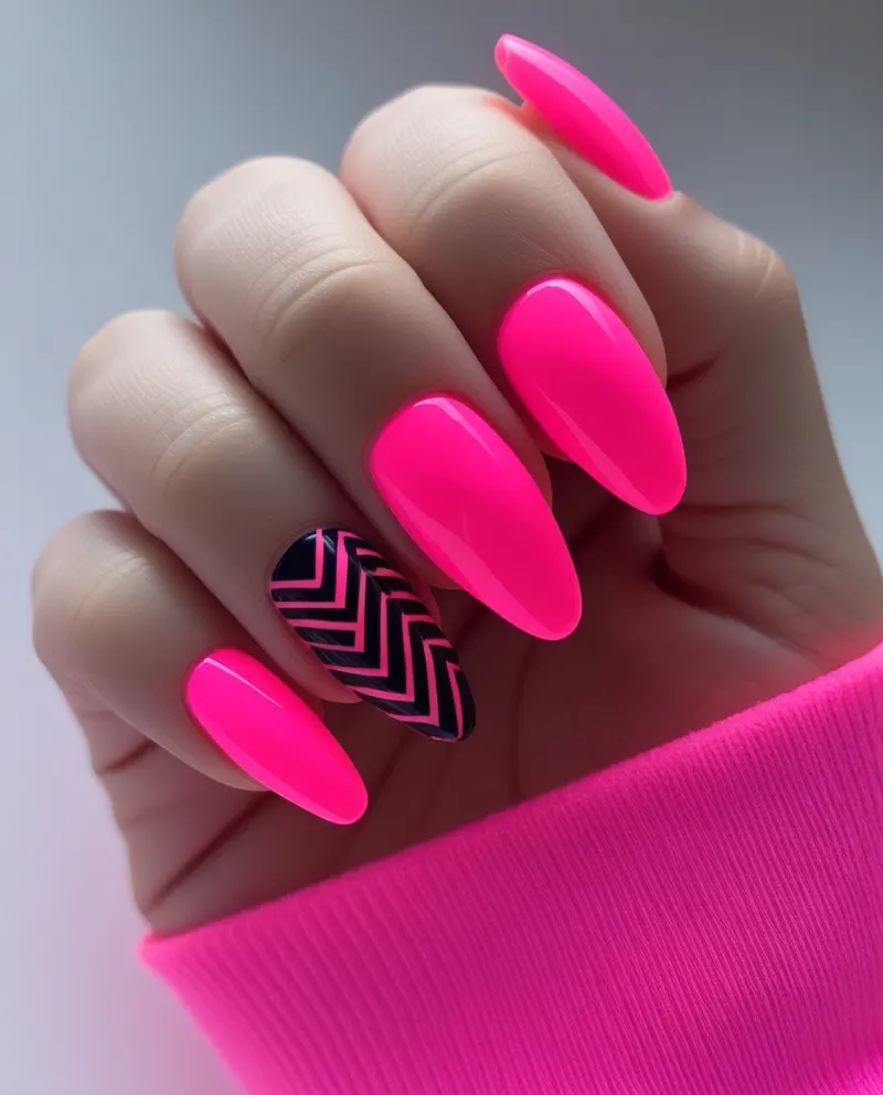 Trendy neon pink nails featuring bold black patterns for a stylish look.