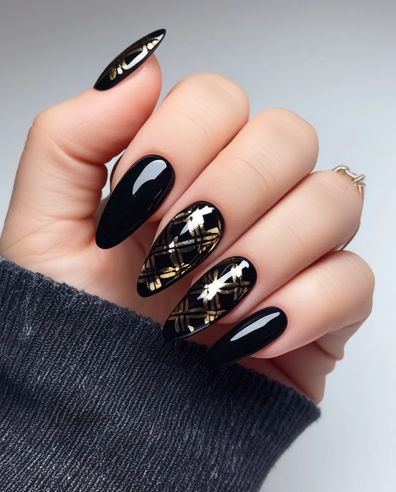 Stylish black and gold nails with elegant design accents.